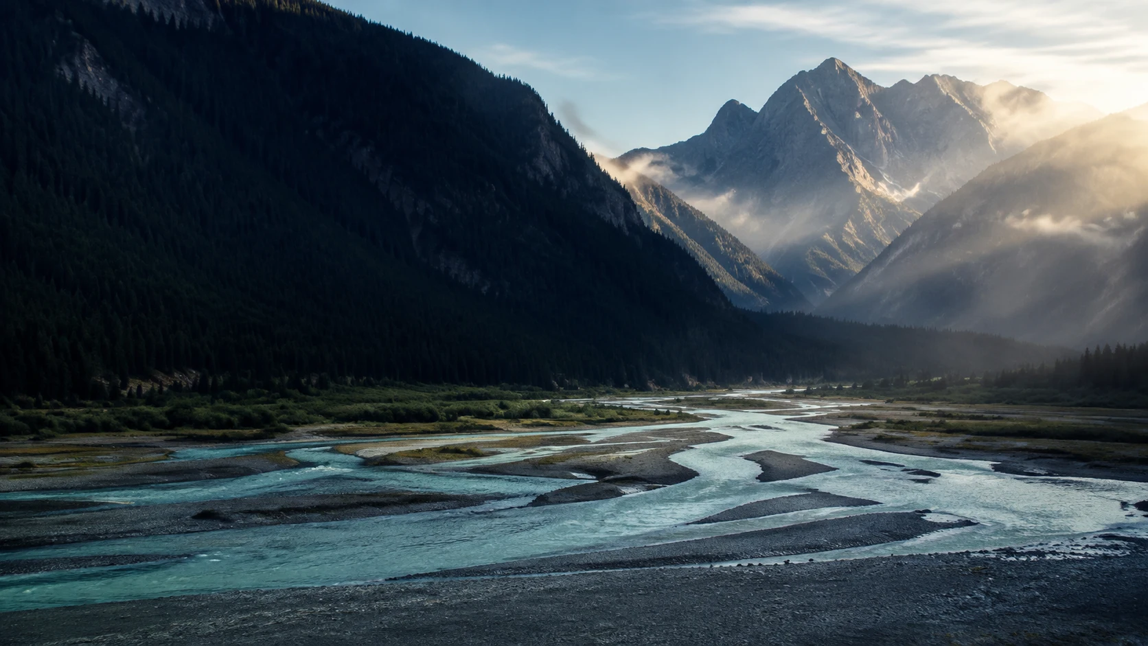Morning light reaching a mountain valley and its winding rivers